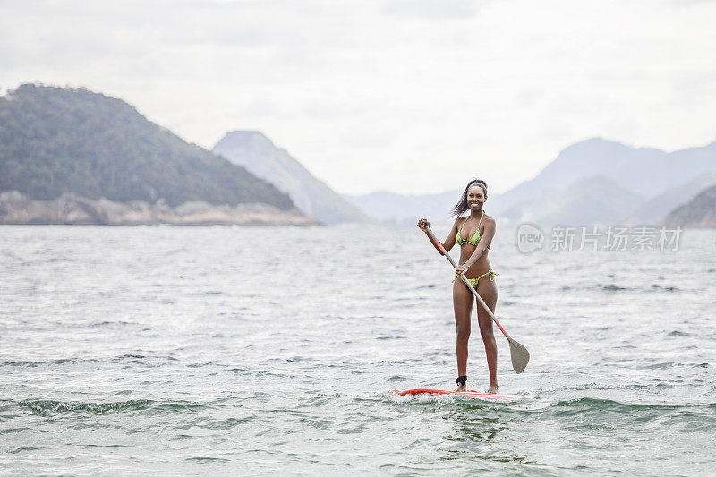 20多岁的女子在冲浪板上保持平衡，里约热内卢de Janeiro